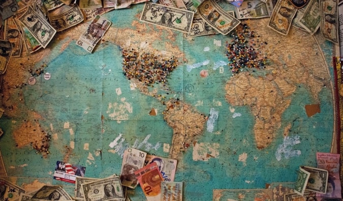 Um mapa em uma parede com dinheiro e alfinetes usados ​​para planejar uma viagem