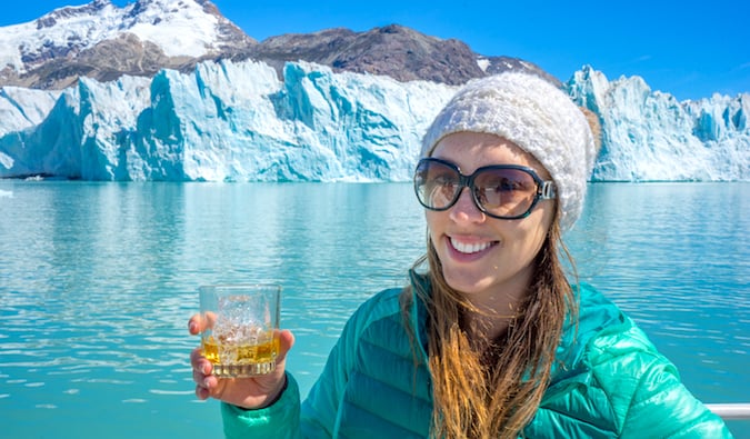 Um único viajante Christine Addis posa com uma bebida perto da geleira O'Higgins na Patagônia