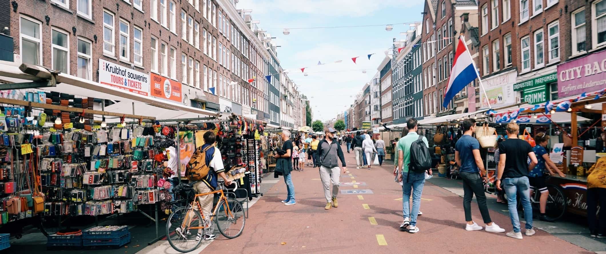 As pessoas andam ao longo de uma rua de pedestres com lojas de mercado em Amsterdã, na Holanda.