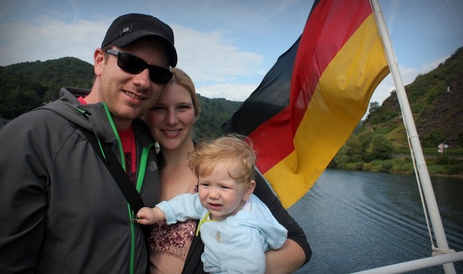 Família viajando de três pessoas posando com a bandeira alemã