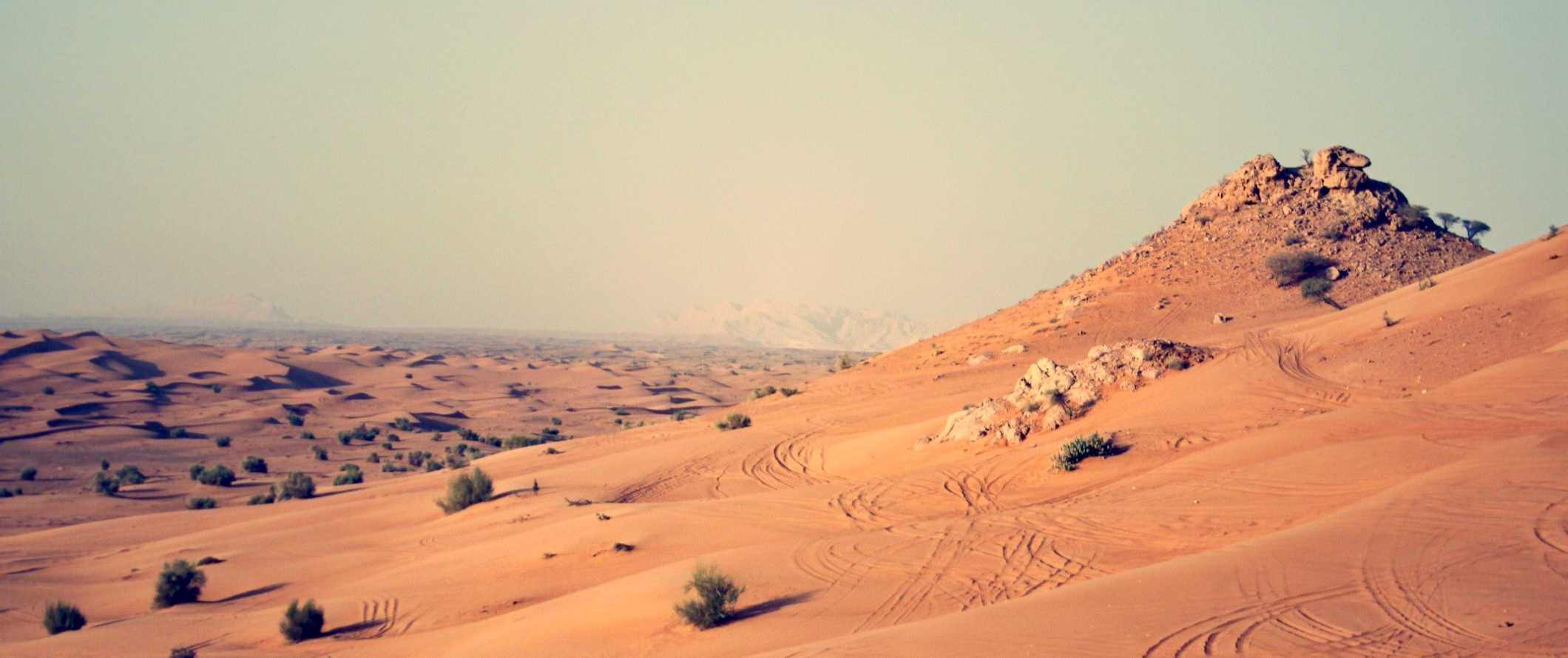 Areias espalhadas e dunas de Dubai, saindo para a distância árida