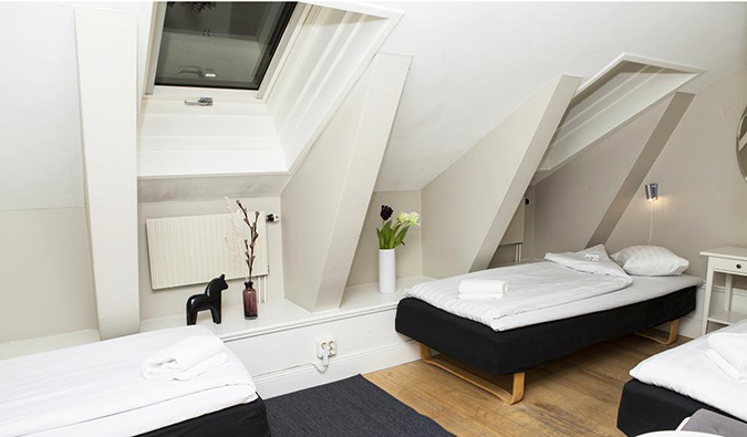Camas de casal em uma sala com tetos inclinados no albergue Lilla Brunn, Estocolmo
