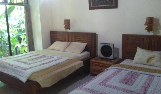 Duas camas de casal com móveis Bali tradicionais na Indraprastha Guest House em Ubuda, Bali