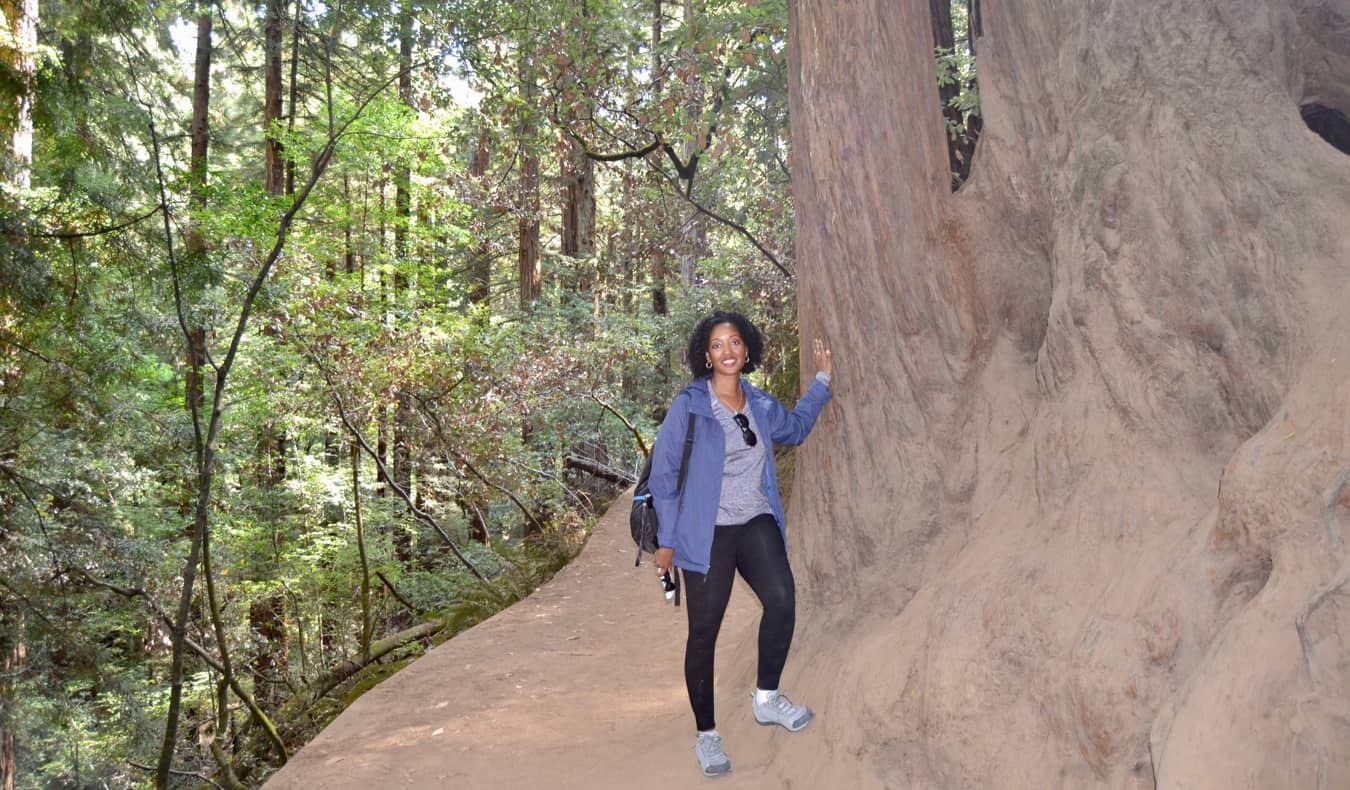 Senitra, uma viajante negra solitária, posa perto de uma enorme árvore