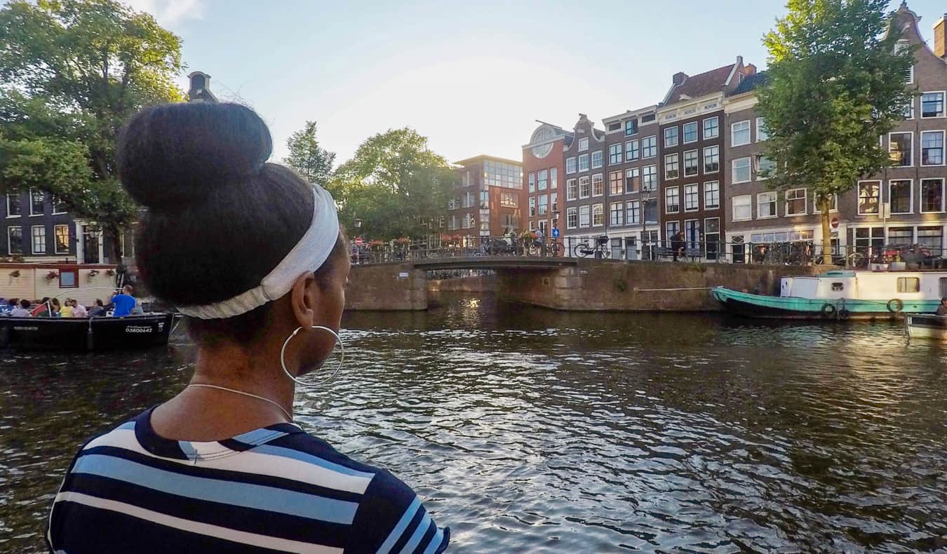 Senitra, uma viajante negra sozinha, posa perto de um canal na Europa