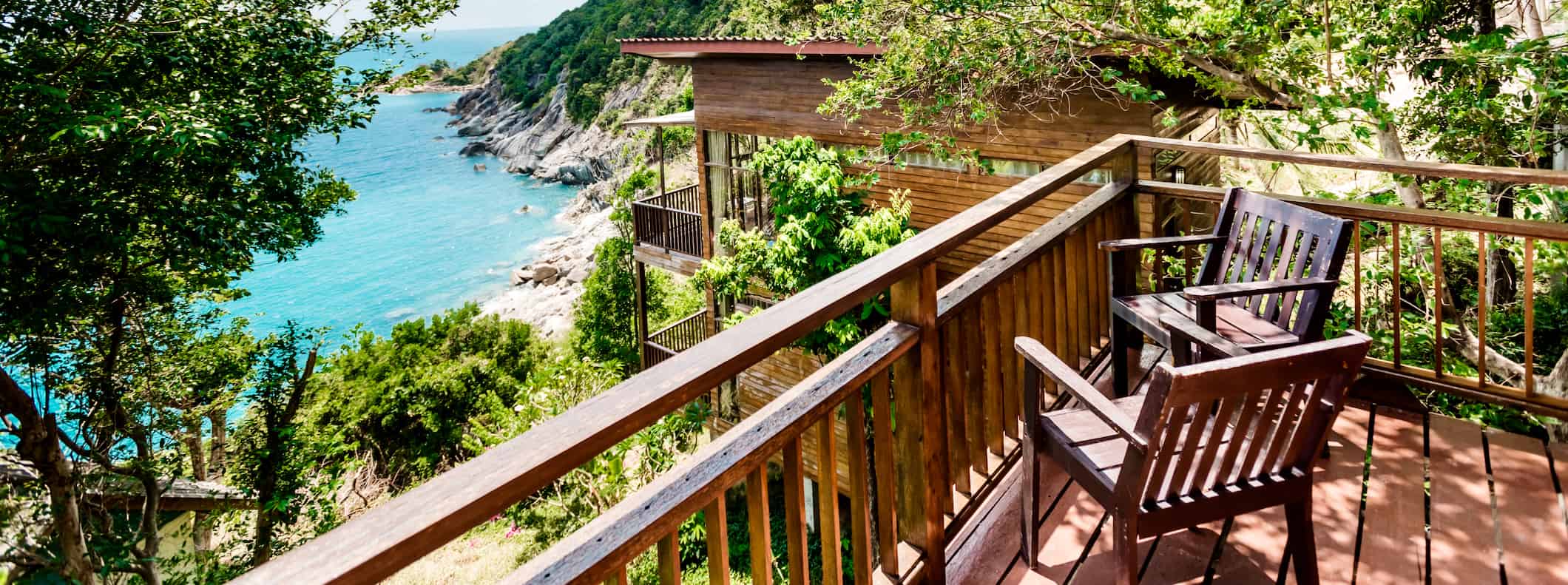 Duas cadeiras de madeira na varanda com vista para uma bela paisagem exuberante