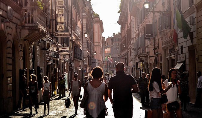 O casal passa por uma rua movimentada na Europa cercada por turistas e residentes locais
