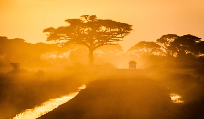 Jeep solitário em uma estrada empoeirada durante um pôr do sol brilhante na África