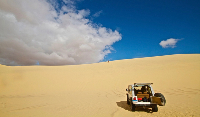O carro alugado explora dunas de areia na África sob um céu azul brilhante