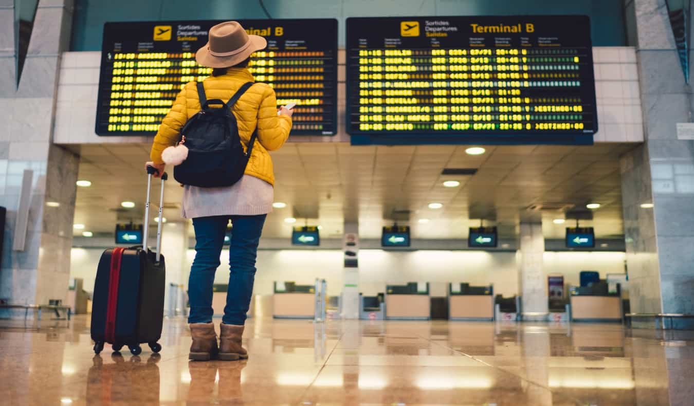 Uma mulher está de pé em frente ao quadro de vôo no aeroporto de Barcelona