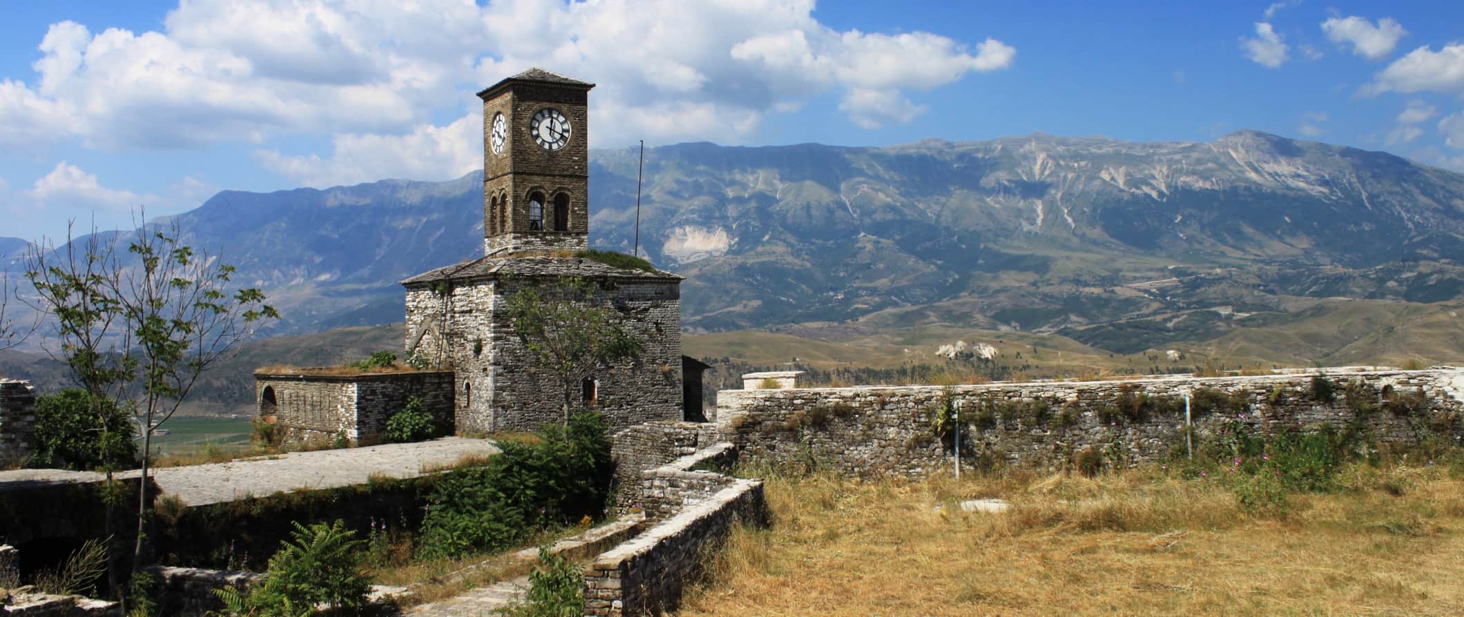Torre de pedra velha e parede de pedra na Albânia com colinas e montanhas à distância