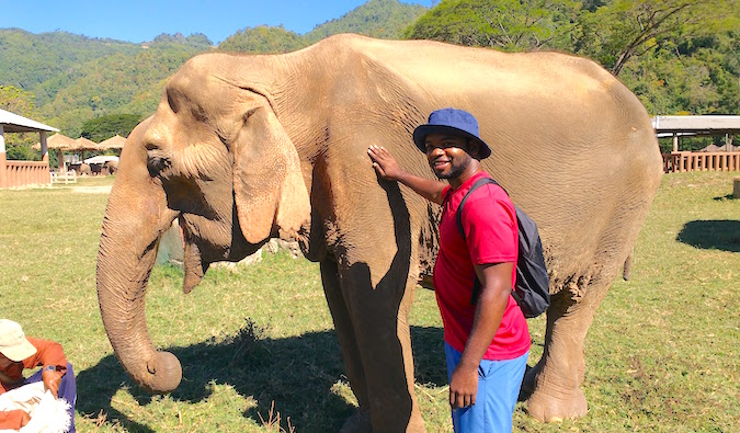 Alex fica ao lado de um elefante resgatado enquanto viaja pelo Sudeste Asiático