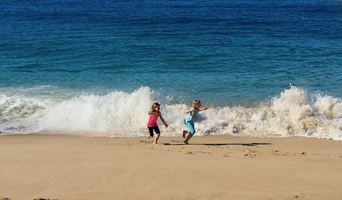 Dois pequenos filhos que viajam se divertem na praia
