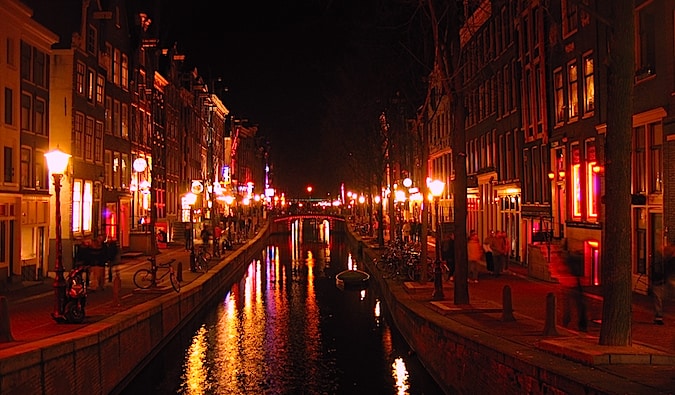 O canal que passa pela área das luzes vermelhas em Amsterdã, iluminada por lanternas vermelhas à noite.