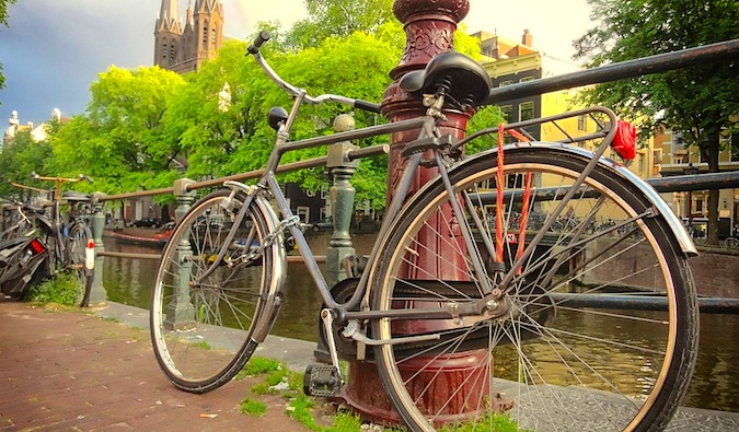 Bicicleta encostada no pilar ao longo do canal em Amsterdã