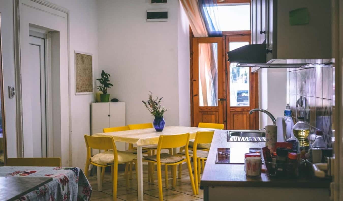Área de cozinha caseira com uma mesa amarela brilhante e portas de madeira no albergue Anchi