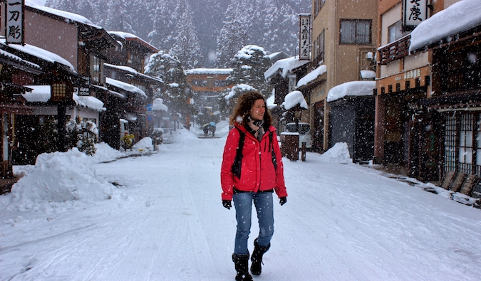 Uma mulher-mulher solitária segue uma estrada nevada no Japão no inverno