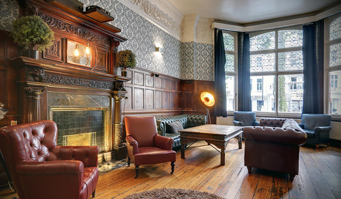 Uma sala comum com sofás de couro e uma lareira de madeira decorada com uma lareira de madeira no Astor Hyde Park Hotel, Londres