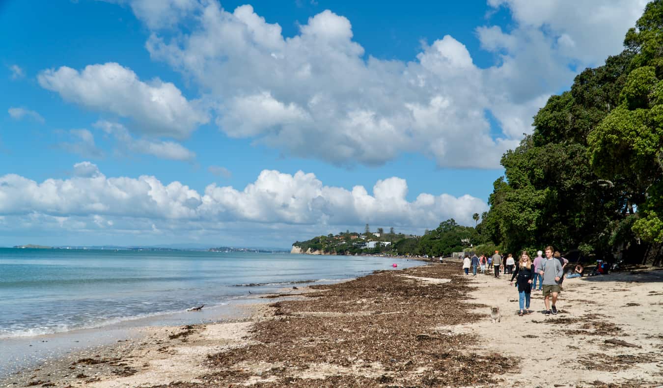 Pessoas caminham ao longo de uma ampla praia perto de Takapuna, em Auckland, Nova Zelândia