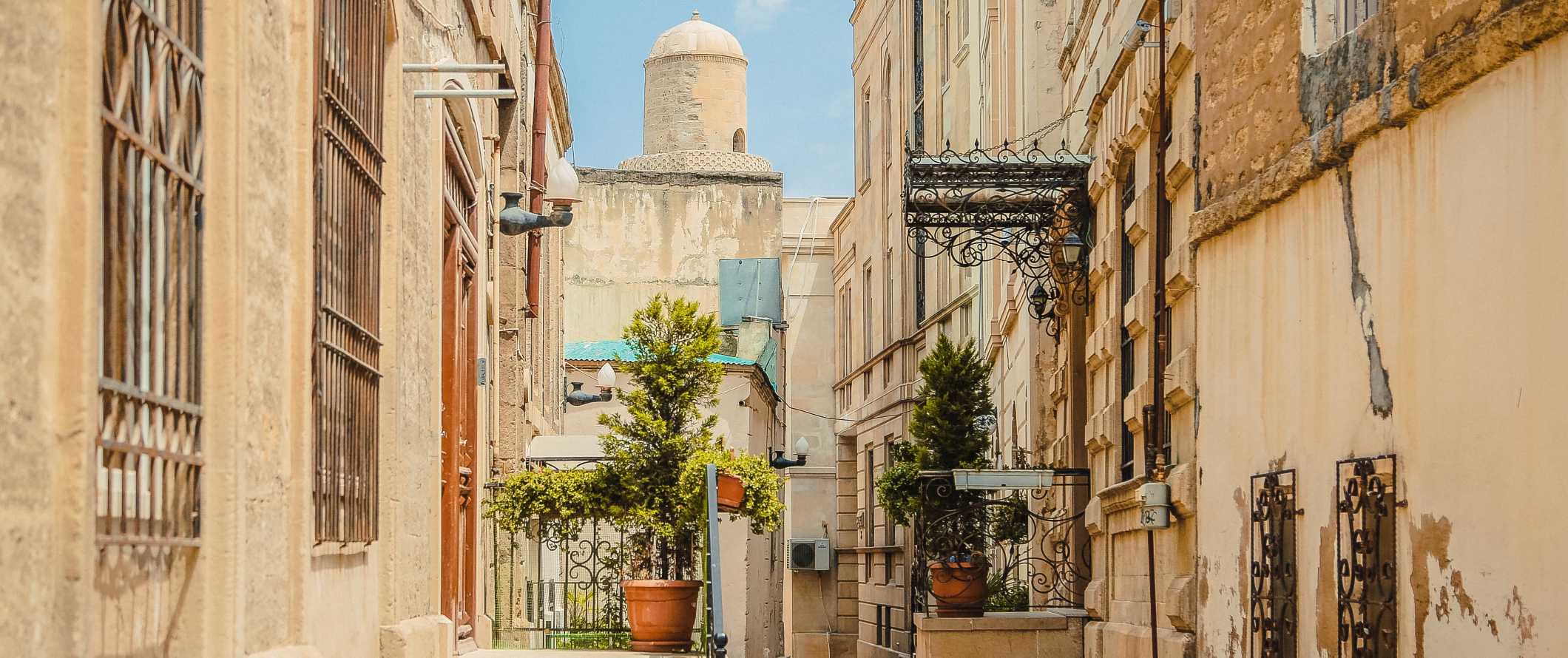 Paisagem de rua com edifícios bege históricos e uma torre de cúpula ao fundo em um dia ensolarado em Baku, Azerbaijão