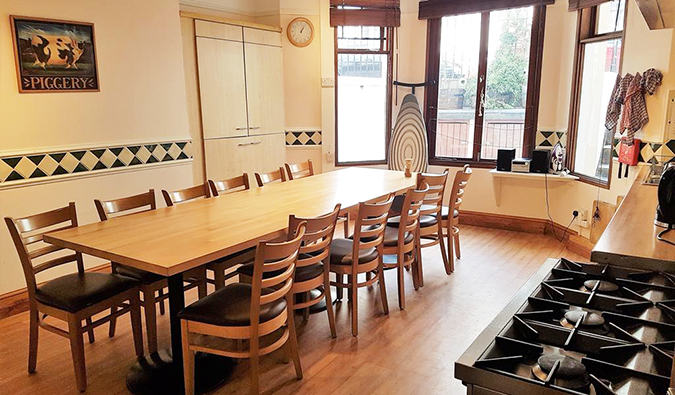 Uma área de cozinha com uma longa mesa de madeira e bayer no albergue Barmy Badger, Londres