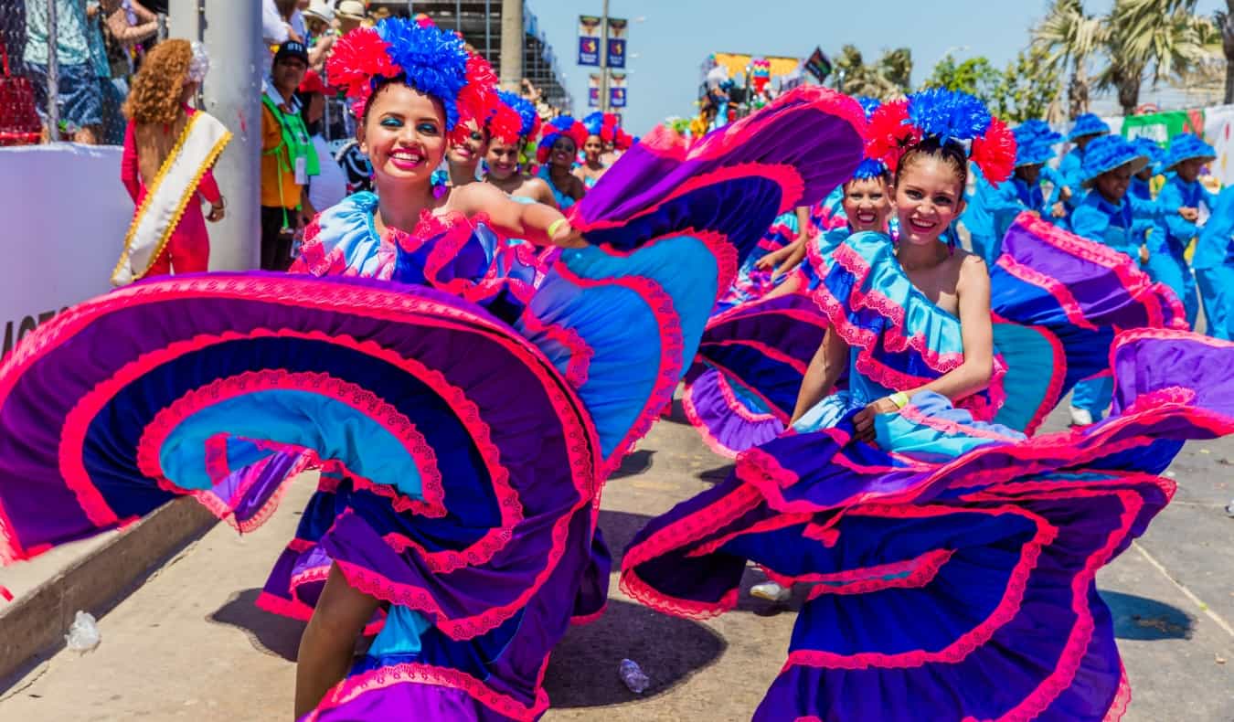 Mulheres com vestidos rosa e roxos brilhantes giram durante o Carnaval em Barranquilla, Colômbia.