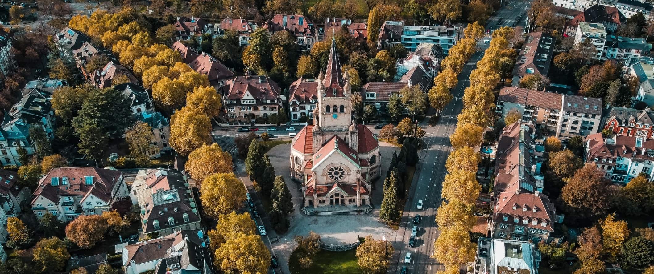 Vista aérea de ruas arborizadas com igreja histórica na praça de Basileia, Suíça