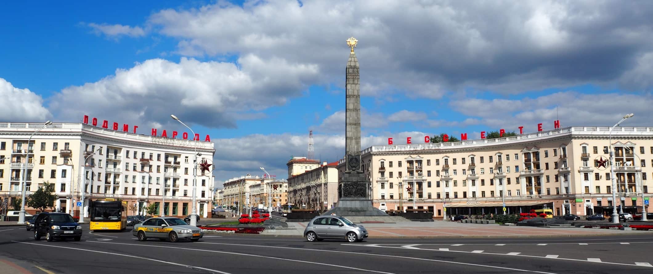 Carros viajam por um grande intercâmbio em frente à Victory Square em Minsk, Bielorrússia