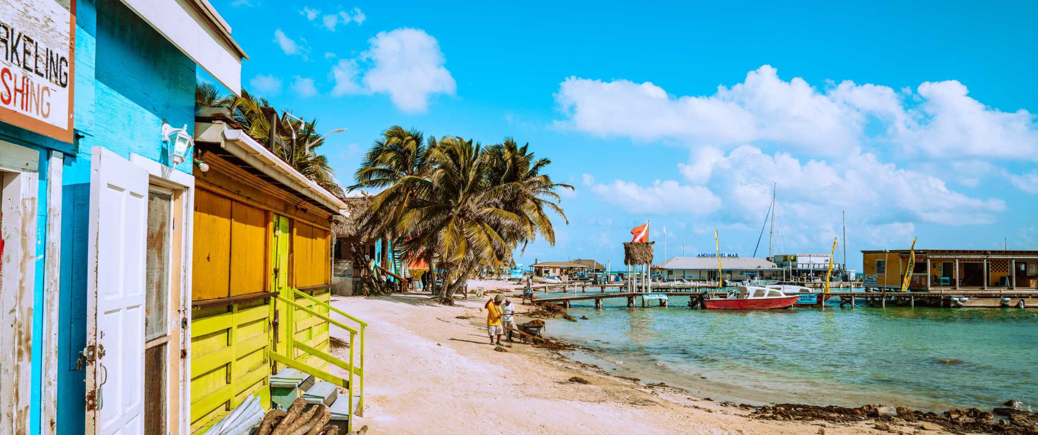 Edifícios pintados ao longo da praia sentados com palmeiras tropicais em Belize