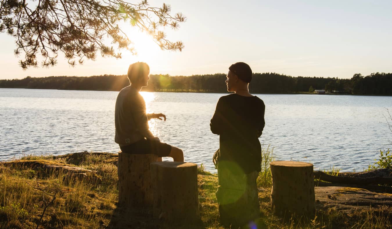 Dois viajantes conversando à beira de um lago no exterior