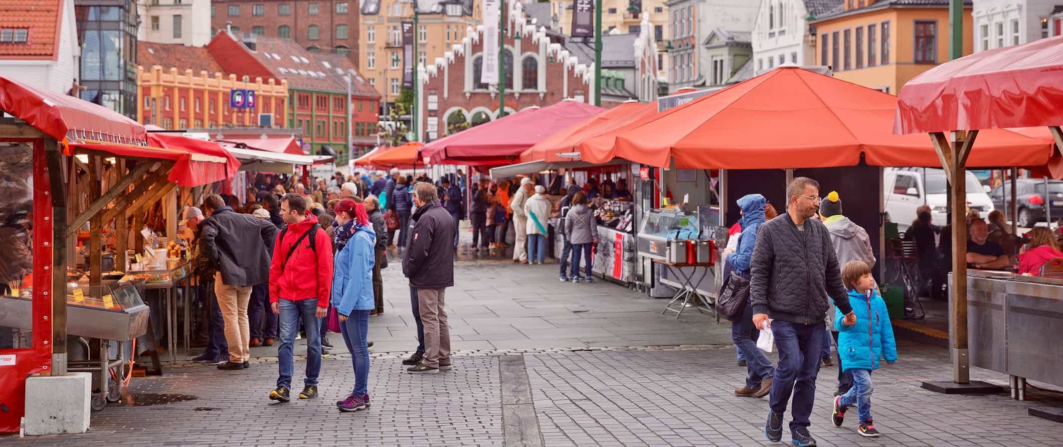 As pessoas inspecionam o animado mercado de peixes em um dia ensolarado em Bergen, Noruega