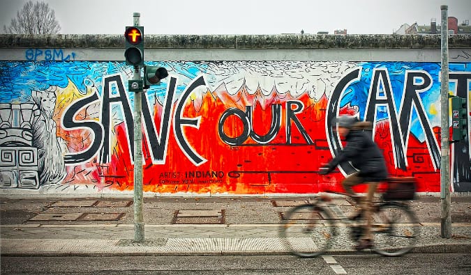 O ciclista passa por um afresco colorido na galeria do lado leste de Berlim, Alemanha