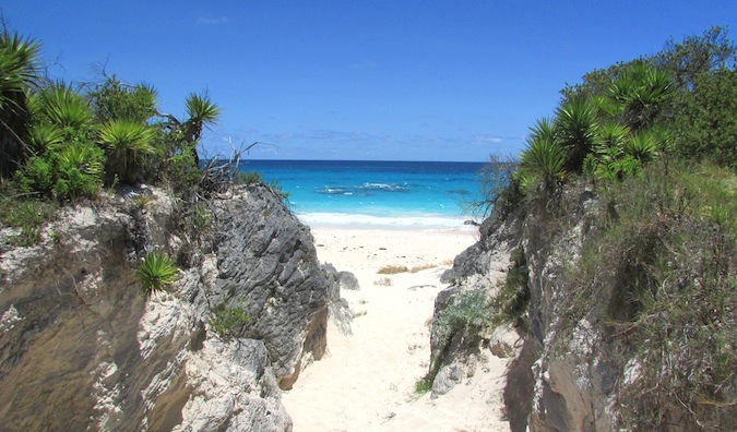 Entrada arenosa para a praia do Caribe cercada por dois grandes penhascos gramados