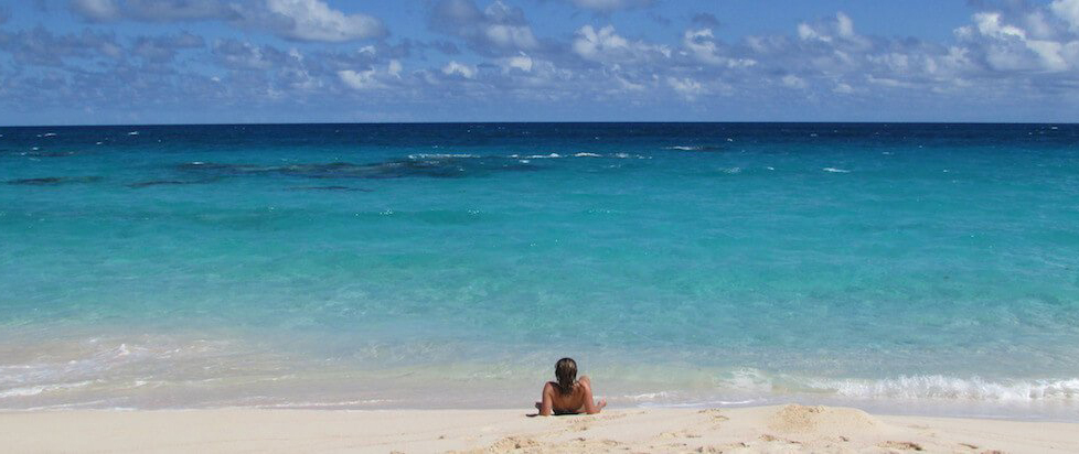 Uma praia intocada na bela costa das Ilhas das Bermudas com um homem descansando em pequena água transparente
