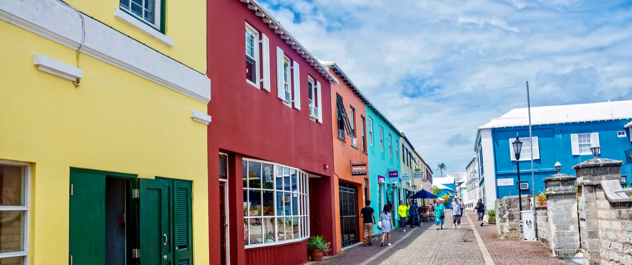 As pessoas andam ao longo de uma rua pedestre cheia de casas brilhantes, nas Ilhas das Bermudas