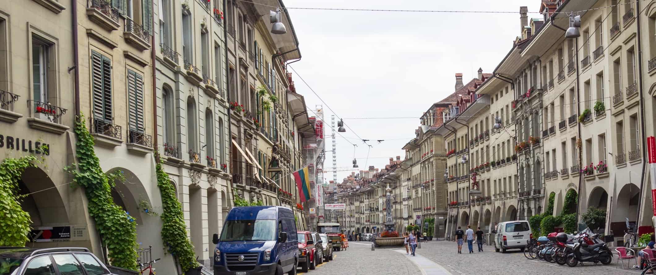 Pessoas caminham por uma rua de paralelepípedos no centro histórico de Berna, Suíça