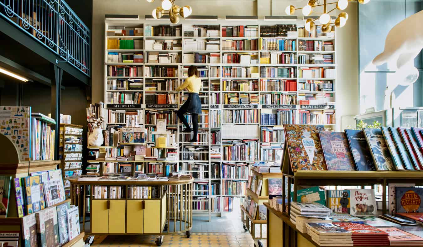 Uma mulher em uma livraria considera livros nas escadas