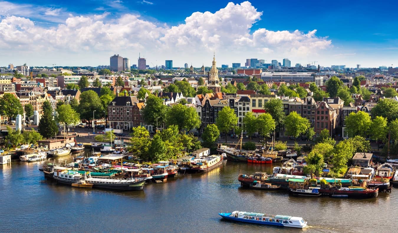 Vista panorâmica do horizonte de Amsterdã com barcos ancorados e flutuando ao longo do rio em primeiro plano