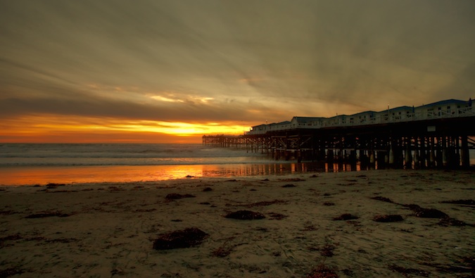 Cais de madeira alto na praia de San Diego durante o pôr do sol