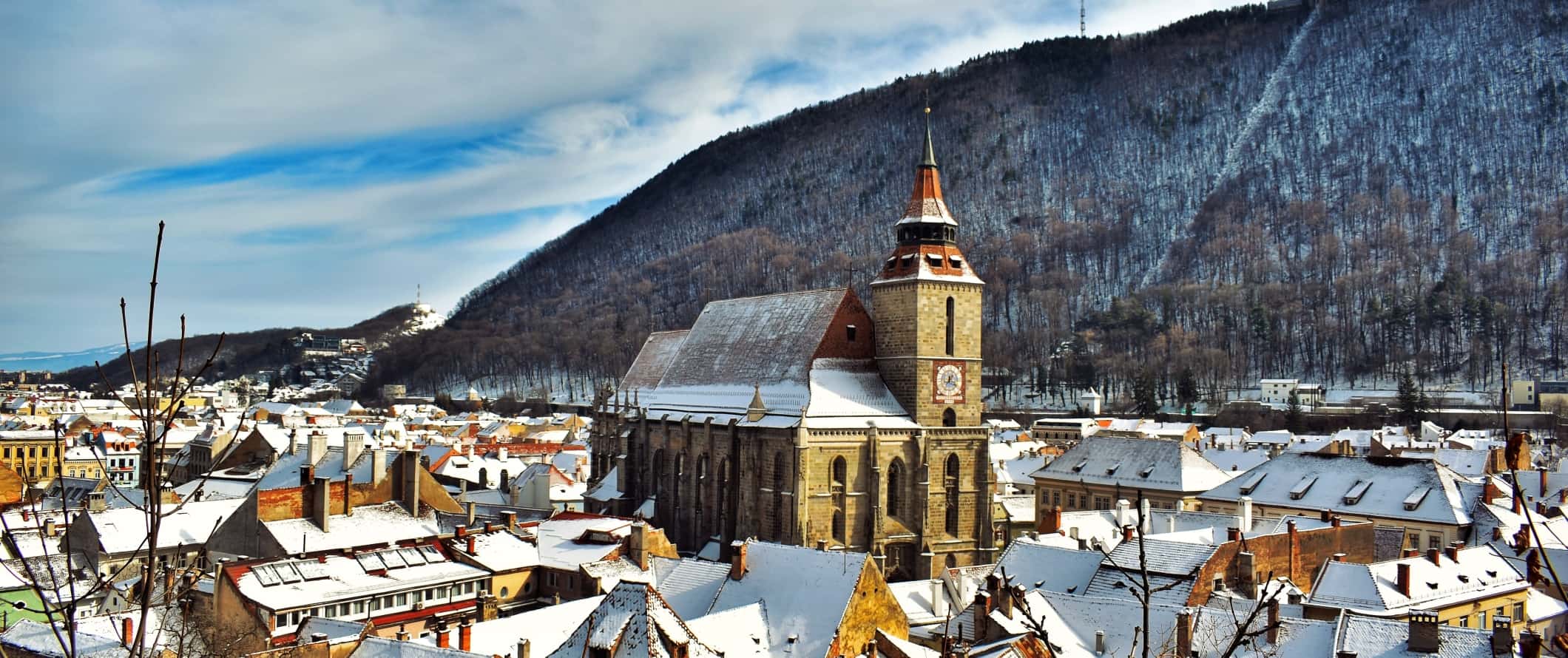A Igreja Negra do século XIV sobe acima dos edifícios nevados em Brasov, Romênia.