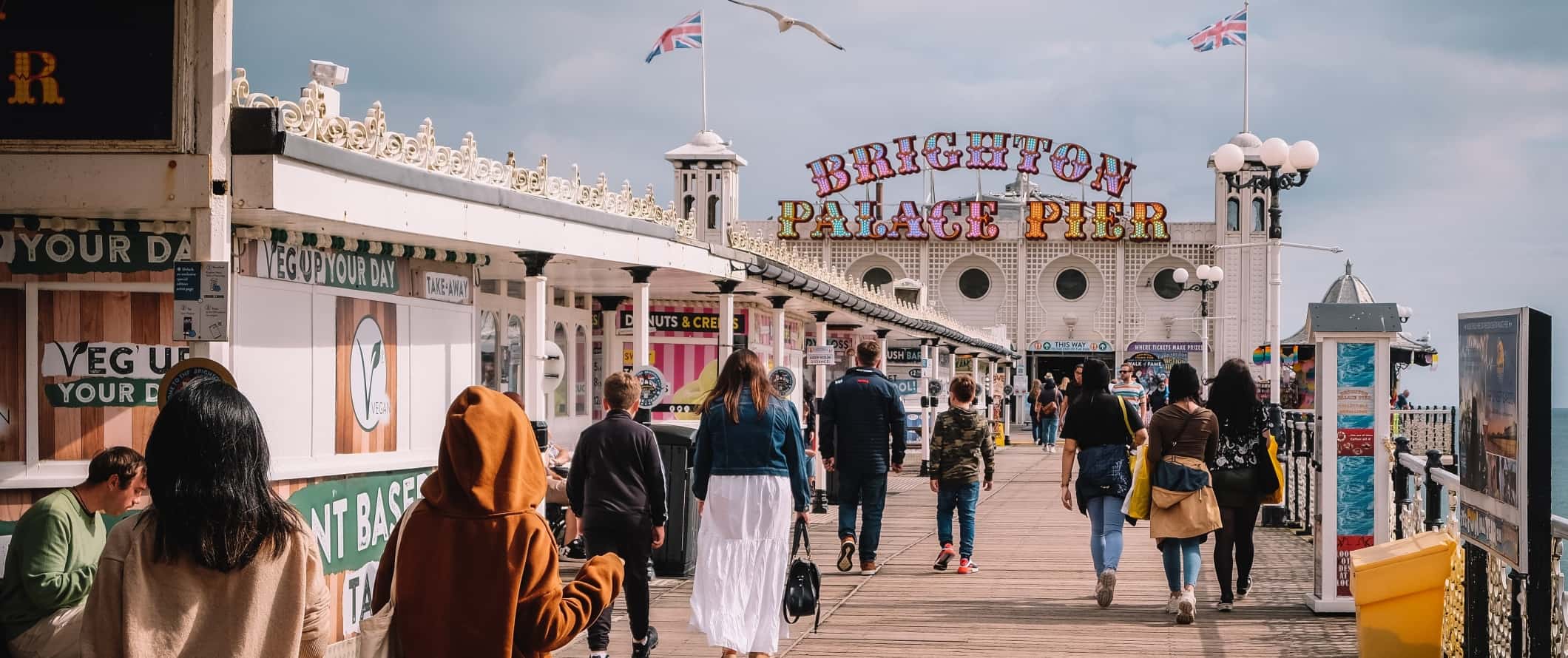 As pessoas andam ao longo do calçadão no píer de Brighton em Brighton, Gr ã-Bretanha
