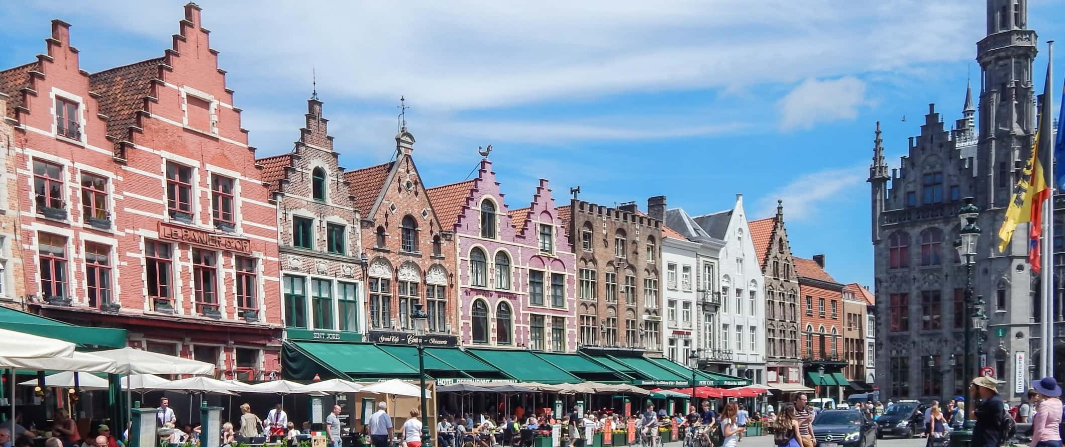 Grote Markt, a principal praça histórica com edifícios de tijolos coloridos em Bruges, Bélgica.