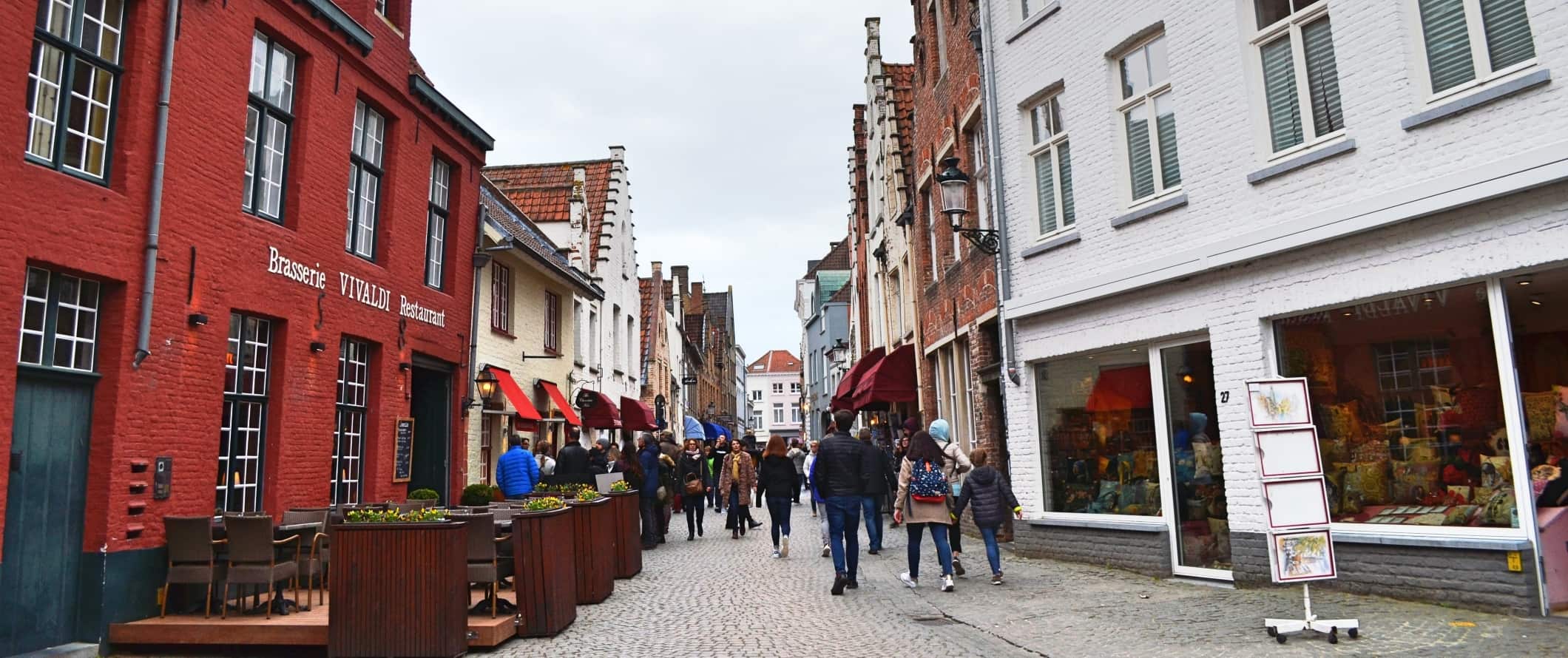 Rua de paralelepípedos com pessoas caminhando em Bruges, Bélgica.