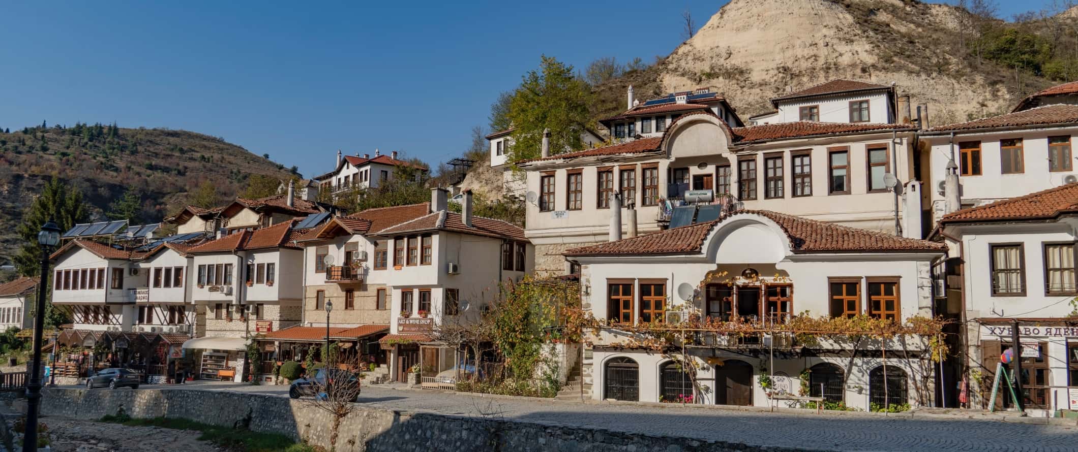 Casas tradicionais búlgaras com telhados de terracota ao longo de uma rua de paralelepípedos numa pequena aldeia