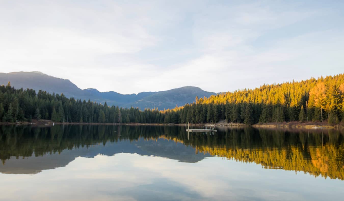 Lago calmo com pequena doca flutuante perto de Whistler, Colúmbia Britânica, Canadá