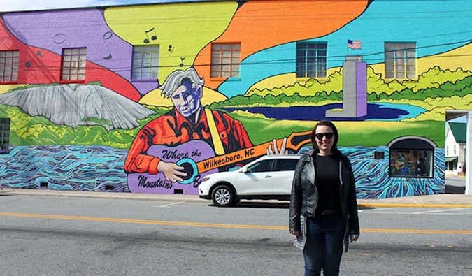 Caroline Eubanks está em frente a um mural em homenagem a Doc Watson em Wilkesboro, Carolina do Norte.