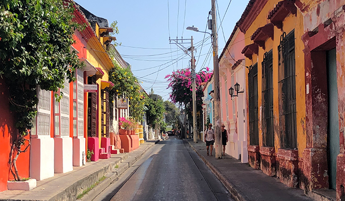 Edifícios pintados com cores vivas ao longo de uma rua estreita e vazia em Cartagena, Colômbia