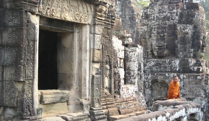 Um monge de manto vagueia por um dos muitos templos antigos de Angkor Wat, no Camboja.