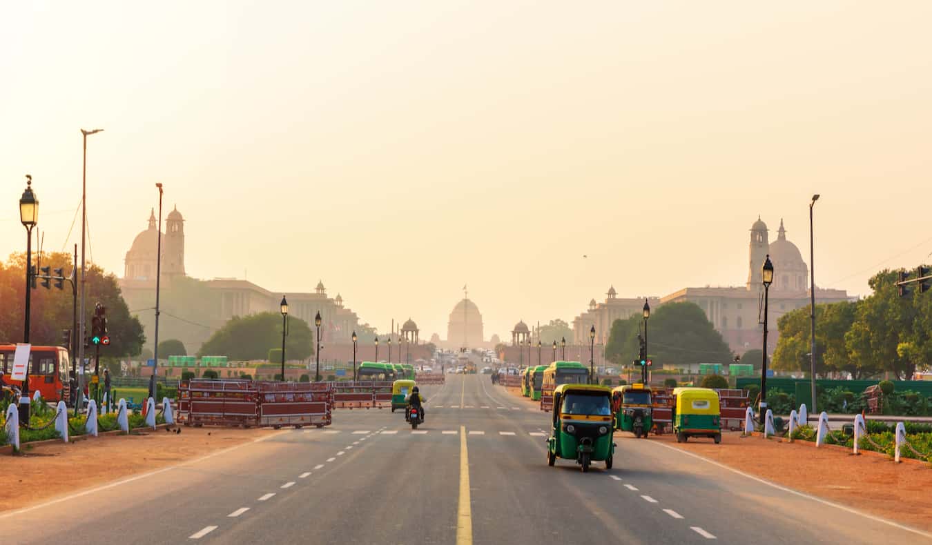 Uma estrada movimentada na Índia no cenário do sol poente, poluição e poeira no ar