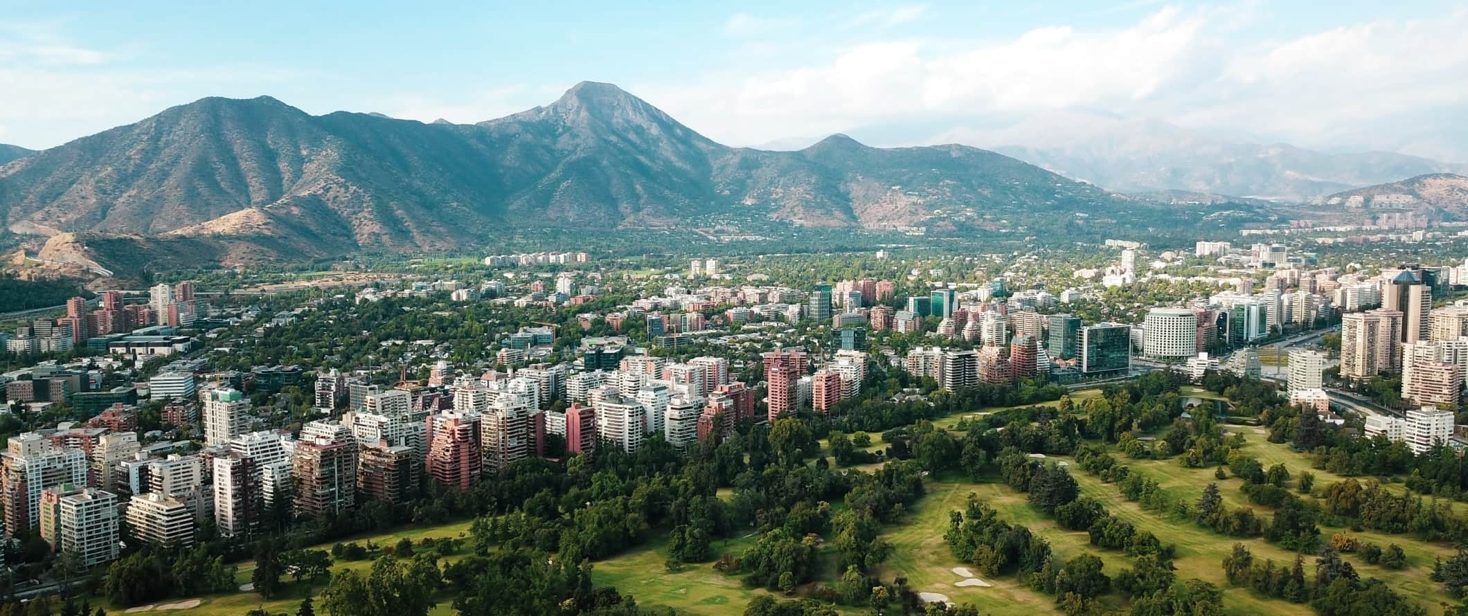 A cidade de Santiago, localizada no vale, com as montanhas se elevando atrás de edifícios altos no Chile